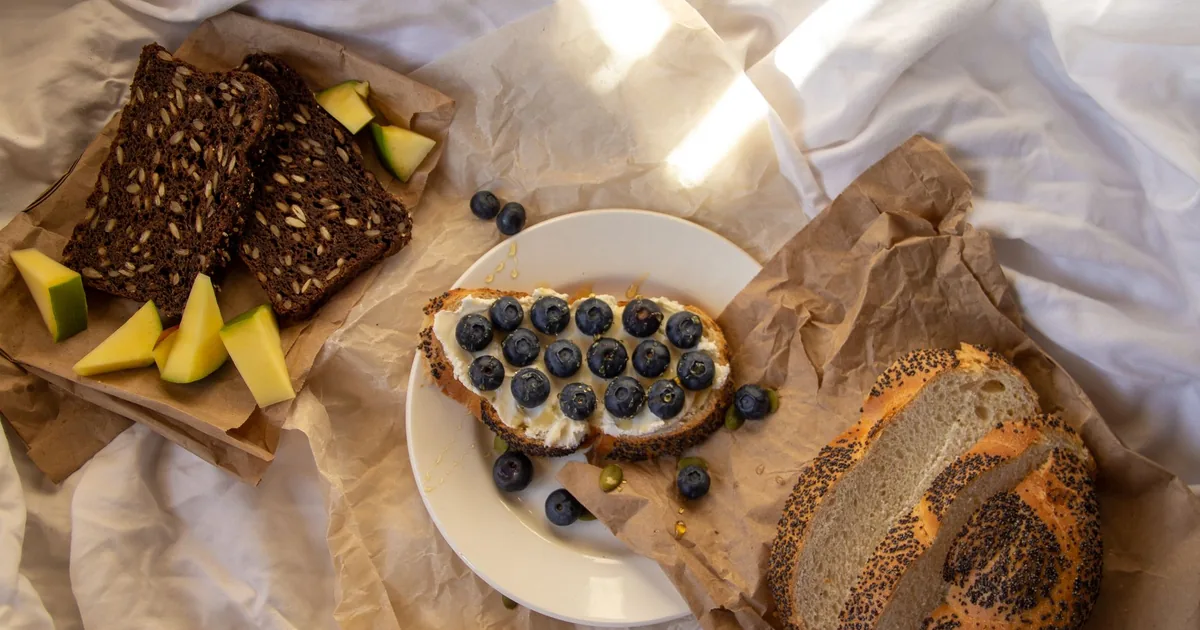 Delicious rustic breakfast featuring blueberry topped bread with mixed grain slices and fresh fruit.