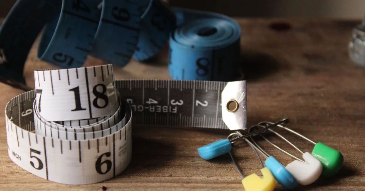 Tape measures and colorful sewing pins on a wooden surface.