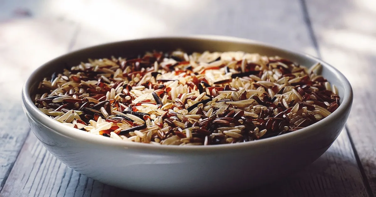 Close-up view of a bowl filled with mixed wild and brown rice grains.