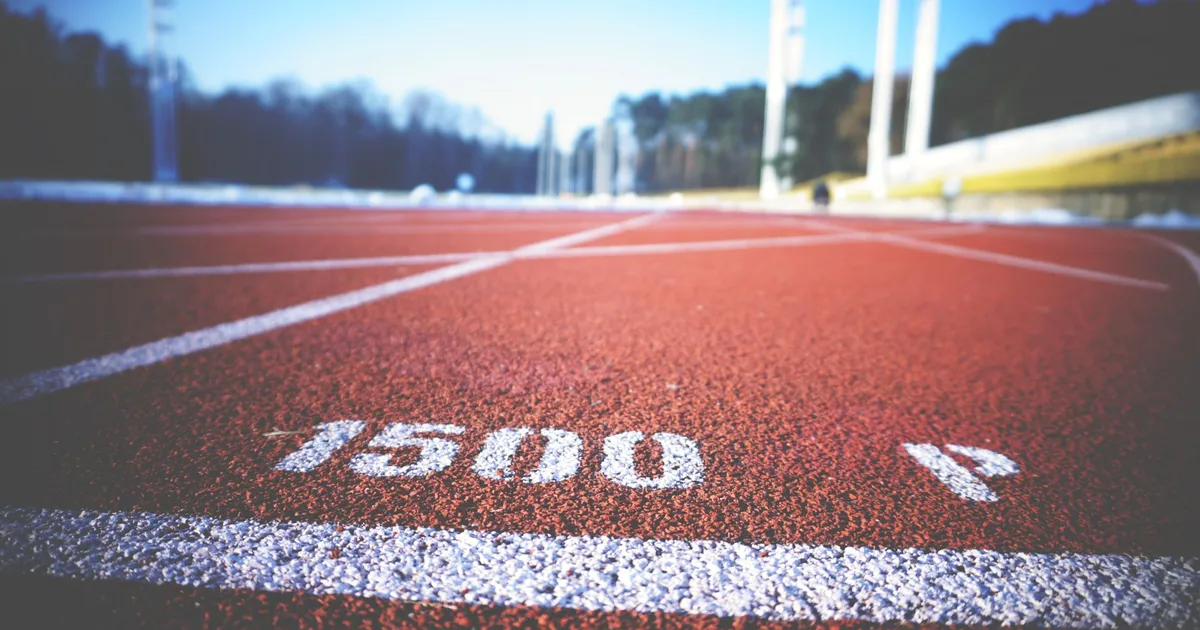 Empty running track lane with 1500 meter marking, sunny day outdoors.