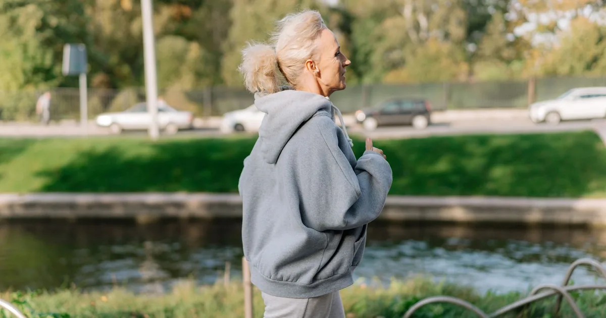 Elderly woman jogging in a park, enjoying a healthy lifestyle outdoors.