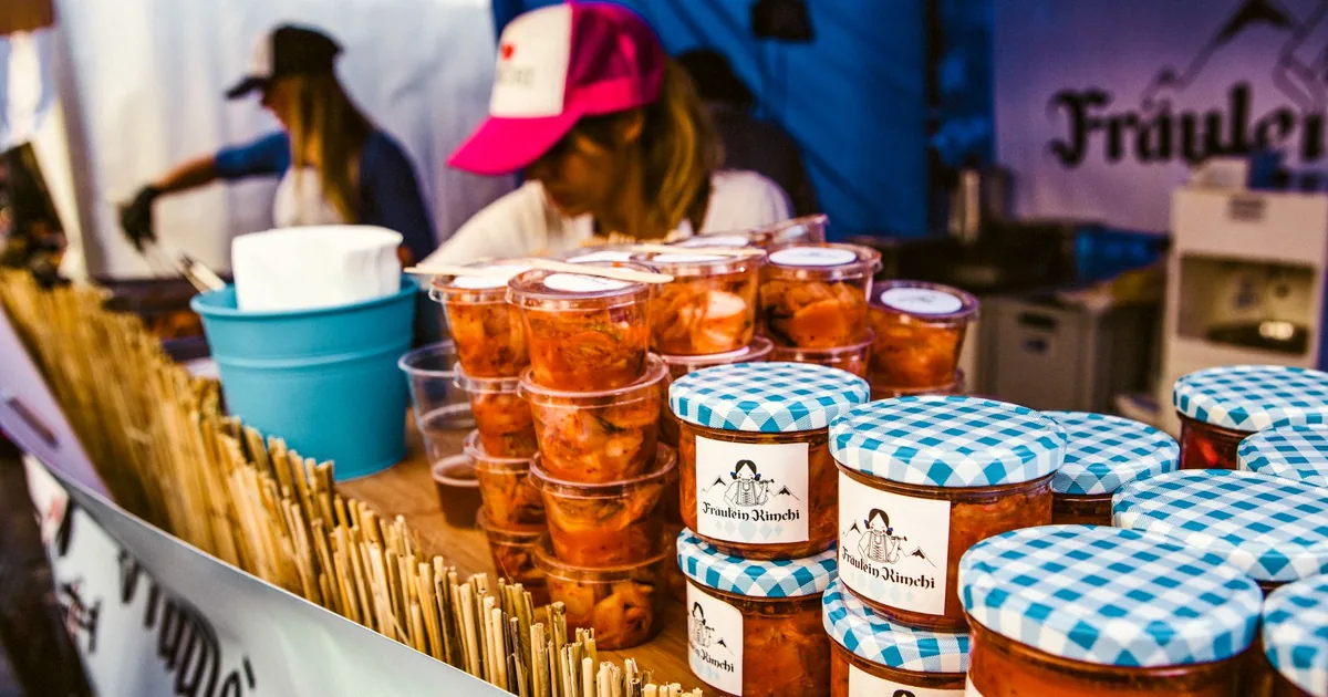 Colorful jars of kimchi at Berlin street market stall with sellers.