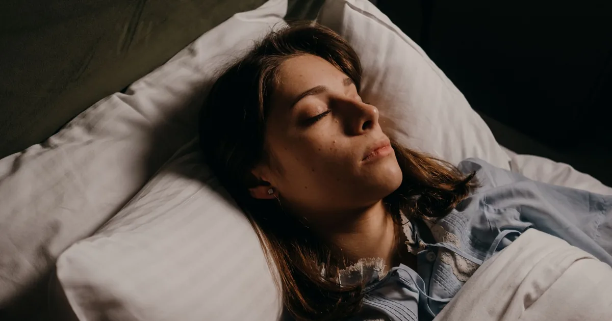 Woman sleeping peacefully in bed, highlighting comfort and serenity in a cozy bedroom setting.