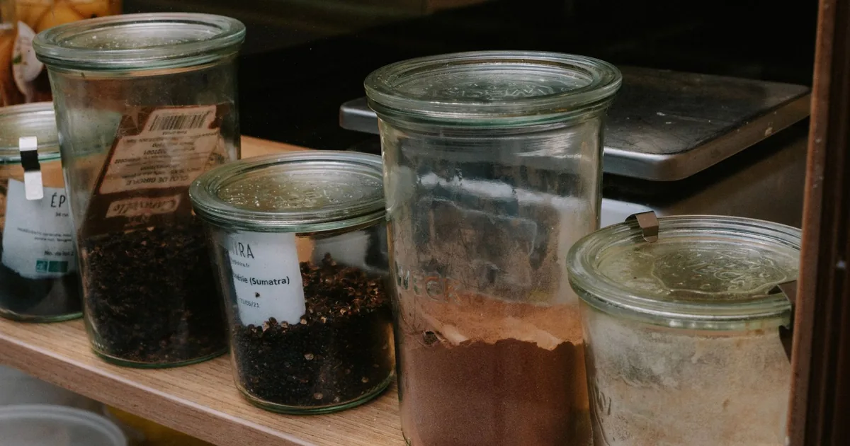A variety of spices stored in glass jars lined on a shelf, perfect for kitchen organization.