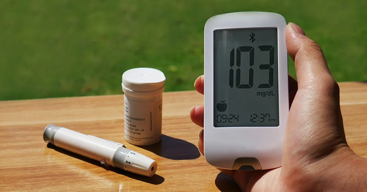 Blood glucose monitor displaying 103 mg/dL outdoors, emphasizing diabetes care.