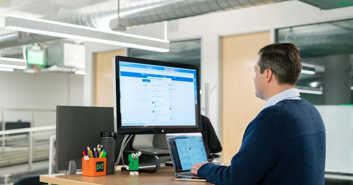 Man working at standing desk on laptop in a modern office setting, focusing on LinkedIn sales tools.