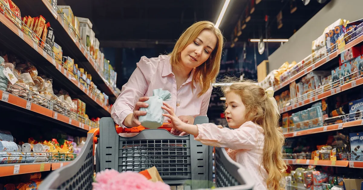 A mother and daughter shopping together in a supermarket aisle, enjoying quality time.