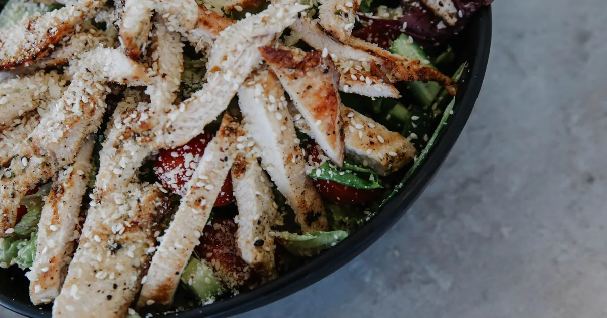 Delicious grilled chicken salad with fresh vegetables and sprinkled seeds.