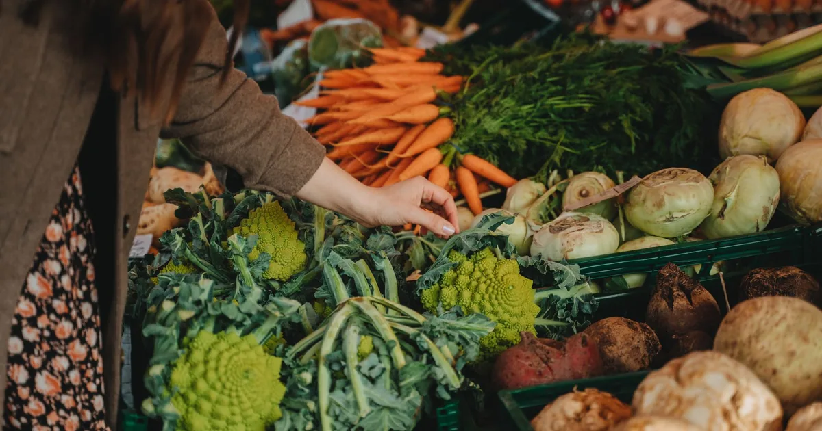 Woman selecting fresh vegetables at a vibrant local farmers market.