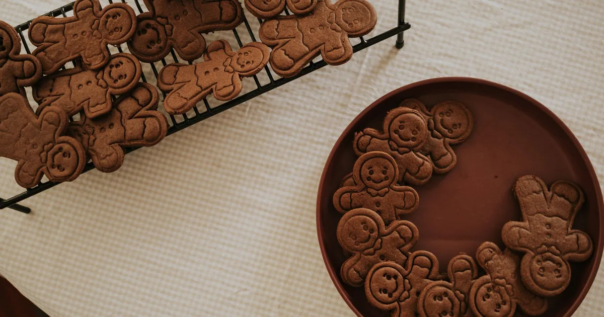 Overhead view of gingerbread cookies on a cooling rack and in a bowl, perfect for holiday baking.