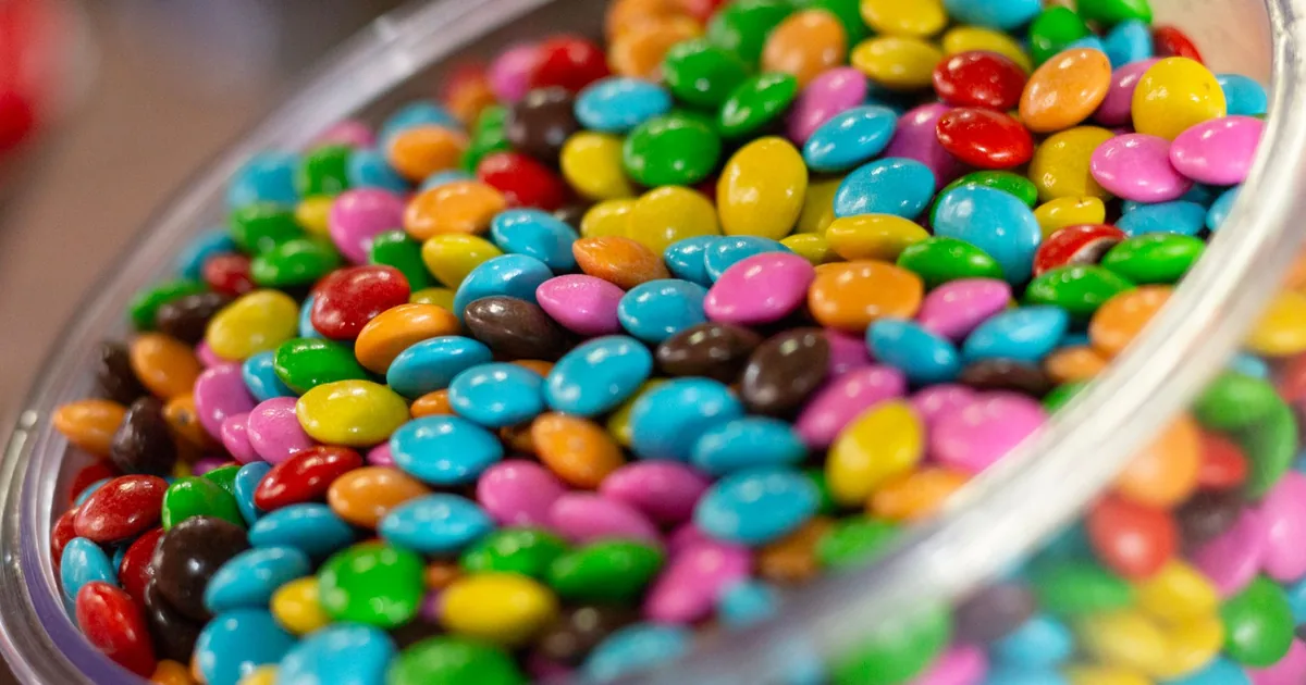 A glass bowl filled with colorful candy-coated chocolates, perfect for a festive party setting.