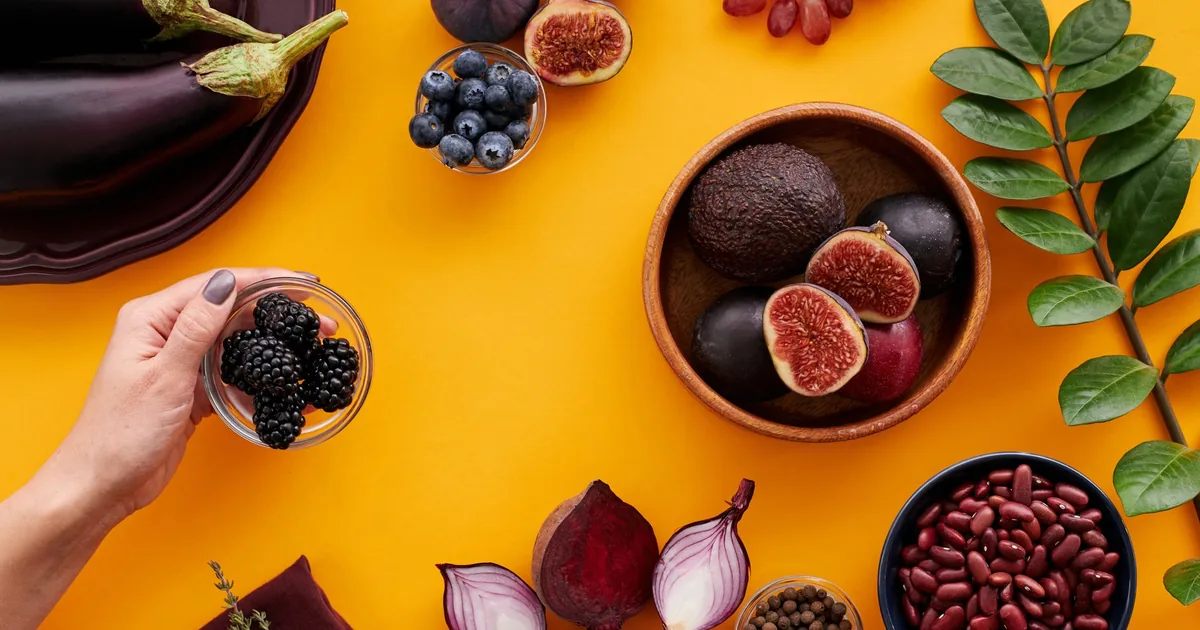 Colorful assortment of fruits and vegetables on a yellow backdrop, highlighting healthy eating.