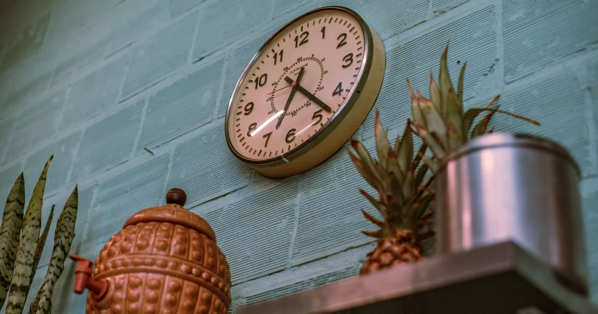 Stylish vintage wall clock on a blue brick wall with kitchen decor.