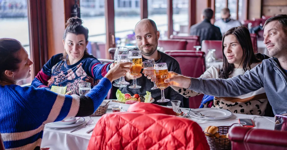 A group of friends toasting with drinks at a cozy restaurant setting.
