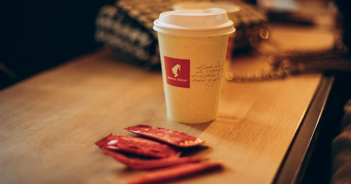 Cozy coffee cup on a rustic table with sugar packets, creating a warm indoor atmosphere.